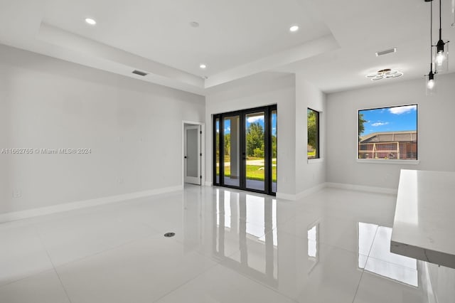 tiled spare room featuring a wealth of natural light and a raised ceiling