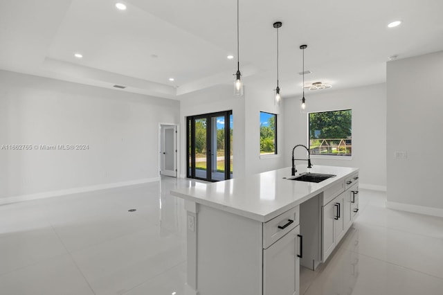 kitchen featuring a healthy amount of sunlight, a center island with sink, sink, and pendant lighting