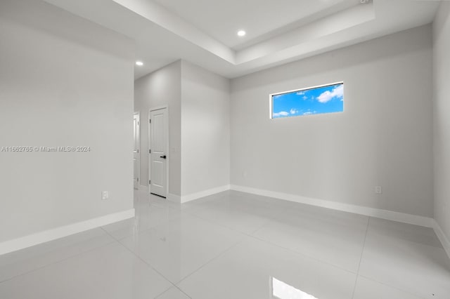 tiled empty room with a tray ceiling