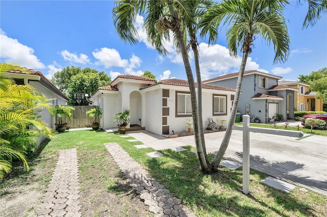 mediterranean / spanish-style house featuring a tile roof, fence, and stucco siding