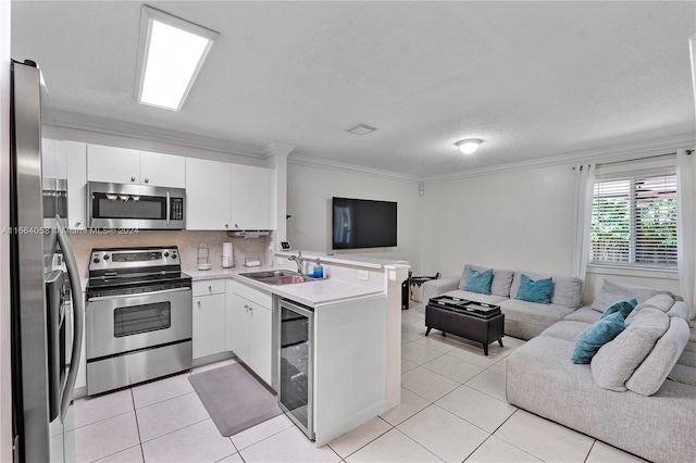 kitchen featuring white cabinetry, kitchen peninsula, appliances with stainless steel finishes, light tile patterned floors, and ornamental molding