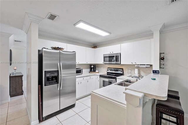 kitchen with a breakfast bar, white cabinets, sink, ornamental molding, and stainless steel appliances