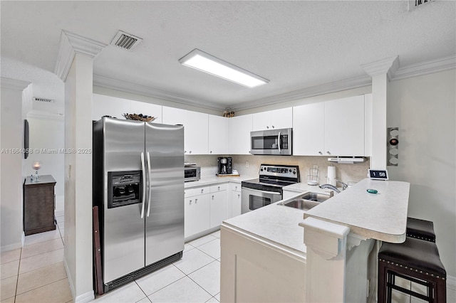 kitchen with crown molding, stainless steel appliances, light countertops, a sink, and a peninsula