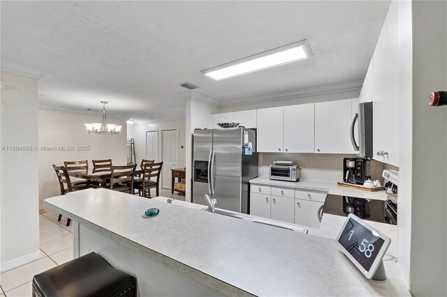 kitchen featuring hanging light fixtures, white cabinetry, kitchen peninsula, stainless steel appliances, and a chandelier