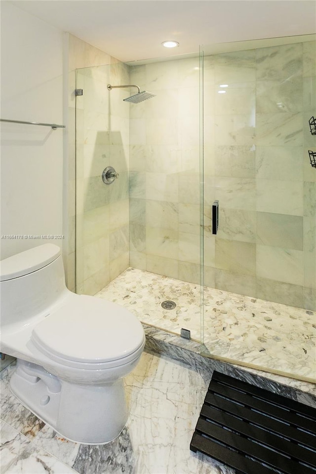 bathroom featuring a shower with shower door and toilet