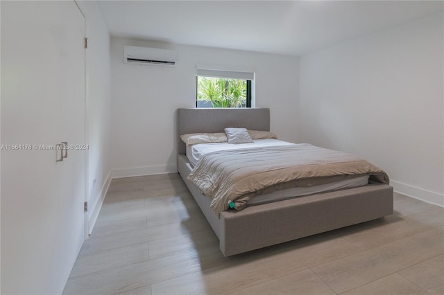 bedroom featuring light hardwood / wood-style floors and a wall mounted air conditioner