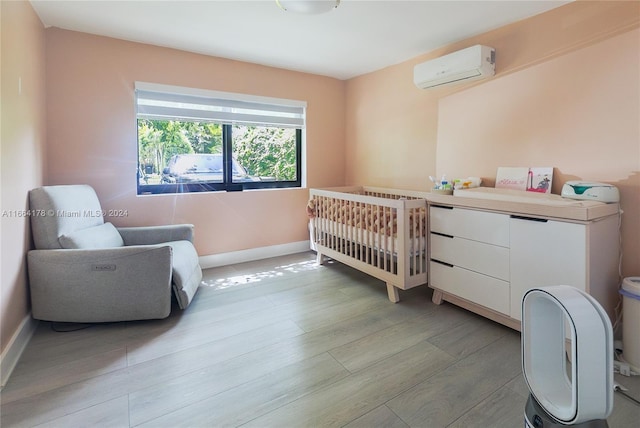 bedroom featuring light hardwood / wood-style floors, a wall mounted AC, and a nursery area