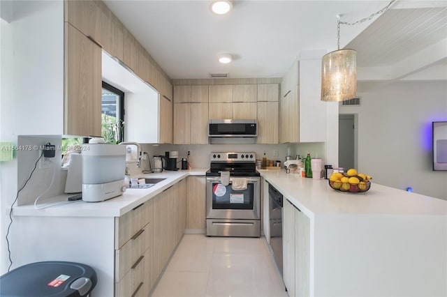 kitchen featuring appliances with stainless steel finishes, light tile patterned floors, light brown cabinetry, decorative light fixtures, and sink