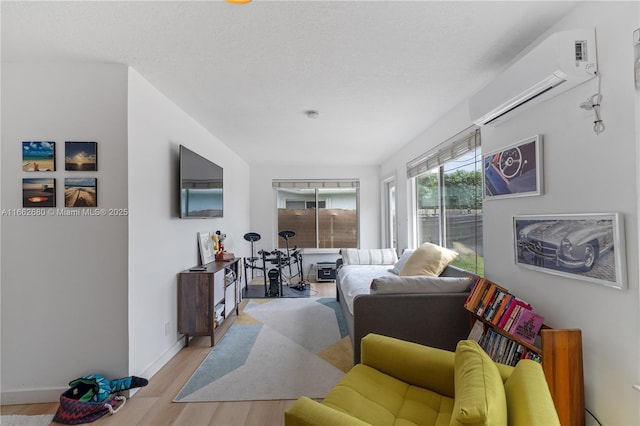 living room with a textured ceiling, light hardwood / wood-style flooring, and a wall mounted AC