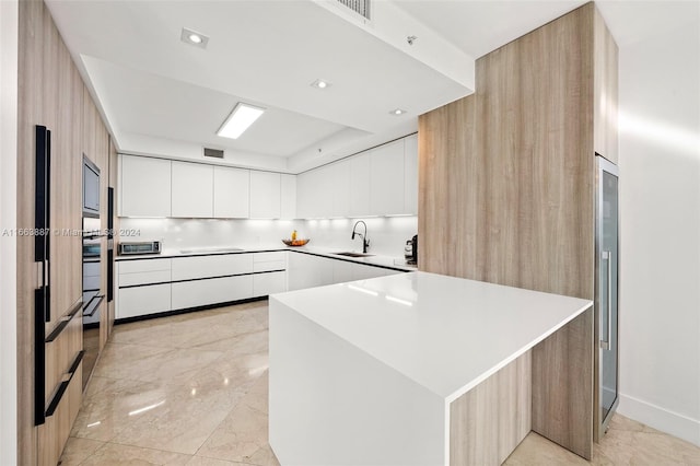 kitchen with white cabinets, black electric stovetop, wall oven, and sink