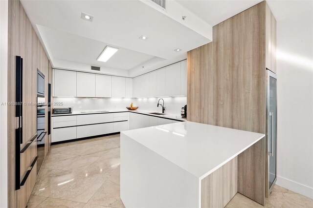 kitchen featuring a sink, visible vents, white cabinets, light countertops, and modern cabinets