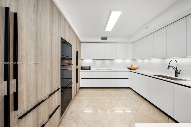 kitchen with light countertops, modern cabinets, a sink, and white cabinets