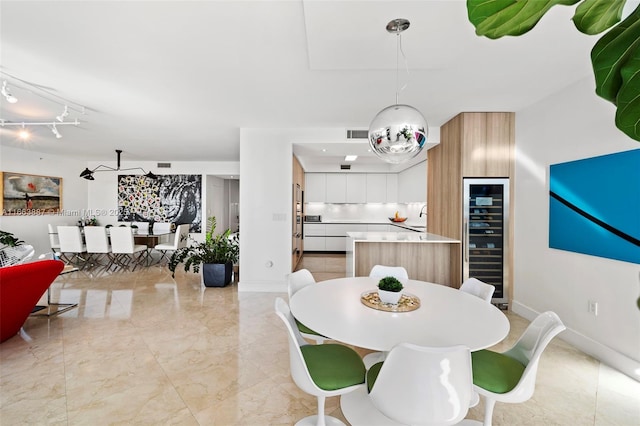 dining space featuring beverage cooler, visible vents, marble finish floor, and baseboards