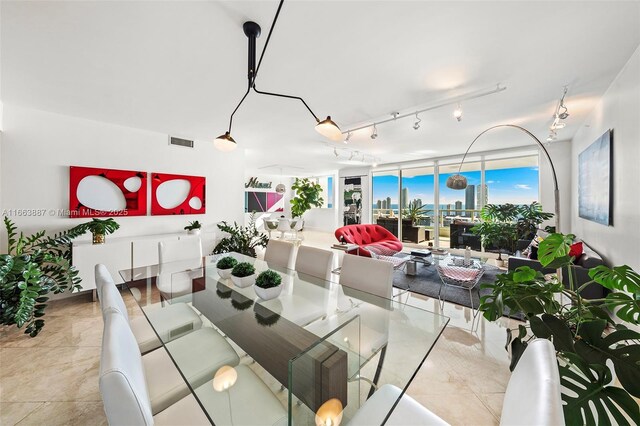 dining space with a view of city, a wall of windows, visible vents, and track lighting