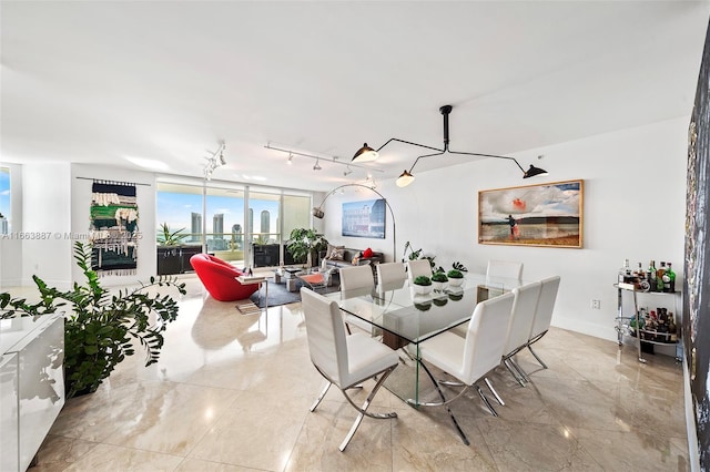 dining space featuring rail lighting and baseboards