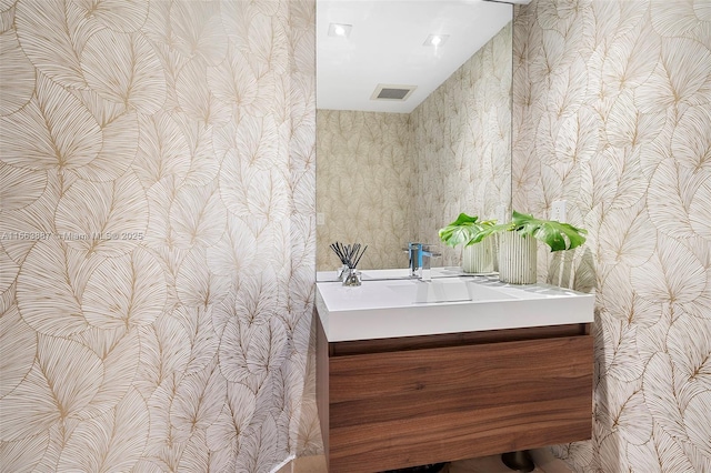 bathroom featuring visible vents, vanity, and wallpapered walls