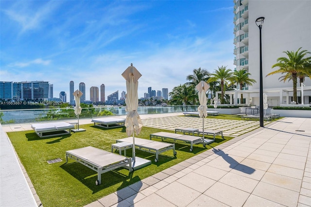 view of property's community featuring a view of city, a lawn, and a water view