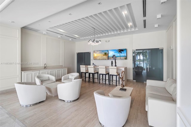 living room featuring a notable chandelier, a decorative wall, and light wood-style flooring