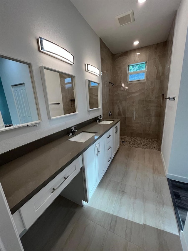 bathroom with a tile shower and vanity