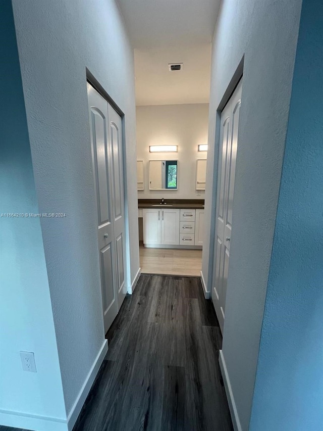 corridor with dark hardwood / wood-style floors and sink