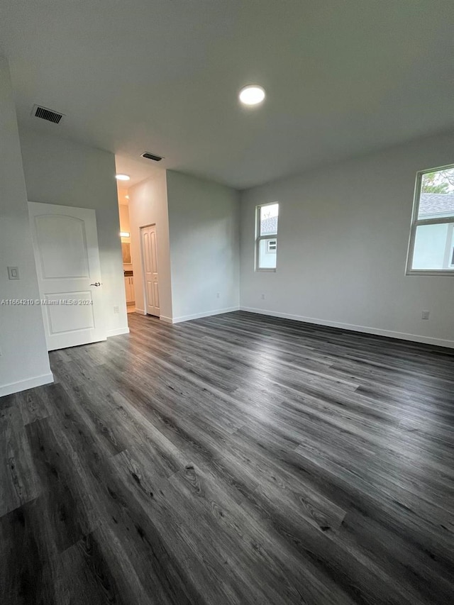 spare room with plenty of natural light and dark wood-type flooring