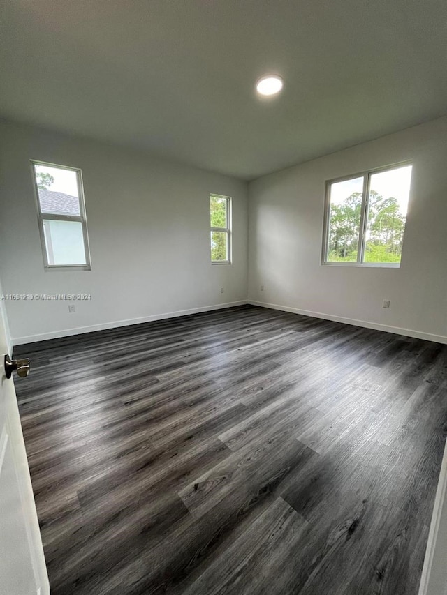 spare room with dark hardwood / wood-style flooring and plenty of natural light