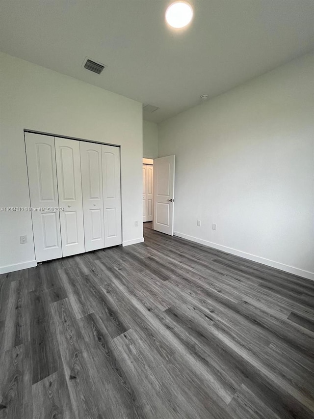 unfurnished bedroom featuring a closet and dark wood-type flooring