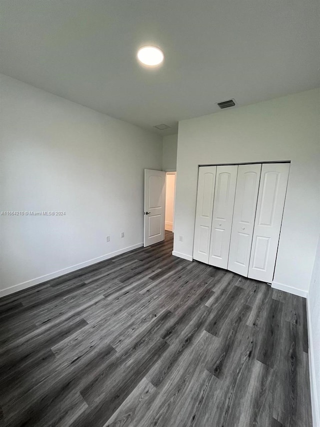 unfurnished bedroom featuring dark hardwood / wood-style flooring and a closet