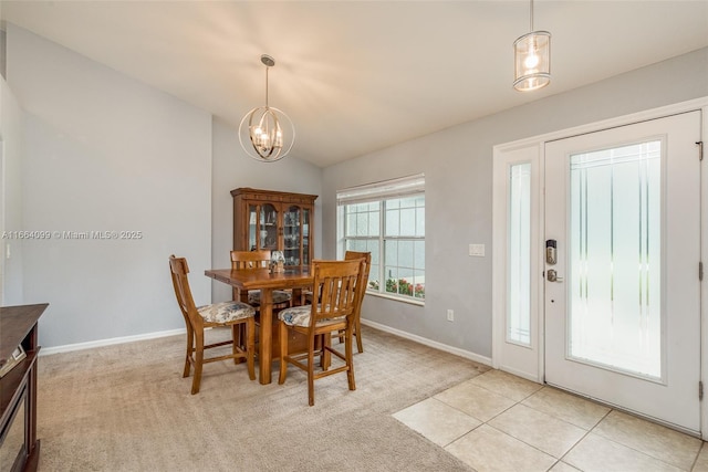 carpeted dining room with an inviting chandelier and lofted ceiling