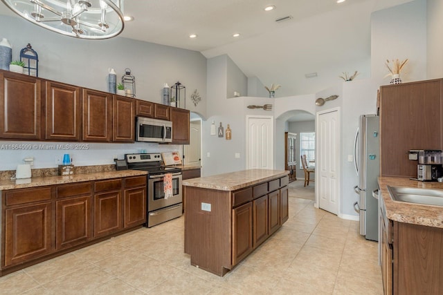 kitchen featuring appliances with stainless steel finishes, high vaulted ceiling, sink, a center island, and light tile patterned floors