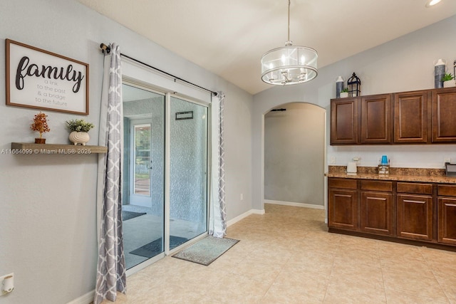 kitchen with decorative light fixtures, a chandelier, vaulted ceiling, and dark brown cabinets