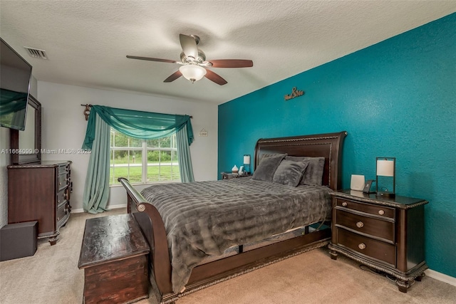 bedroom with light colored carpet, a textured ceiling, and ceiling fan