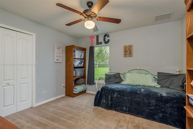 carpeted bedroom with ceiling fan, a closet, and a textured ceiling