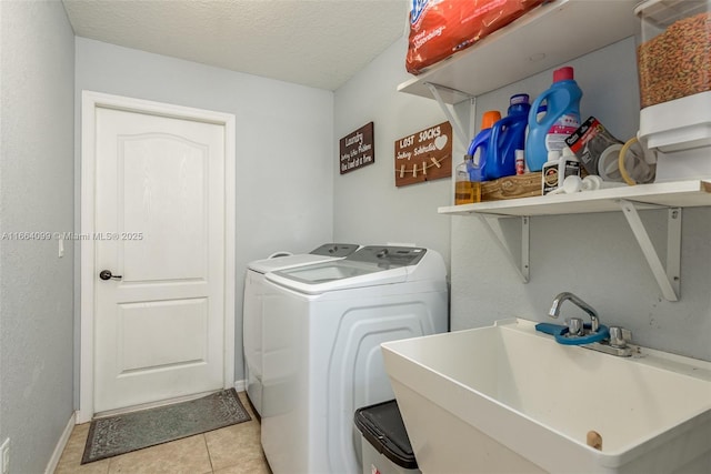 laundry area with washer and clothes dryer, sink, a textured ceiling, and light tile patterned floors