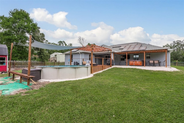 back of property featuring a patio area, solar panels, a yard, a pergola, and a swimming pool with hot tub