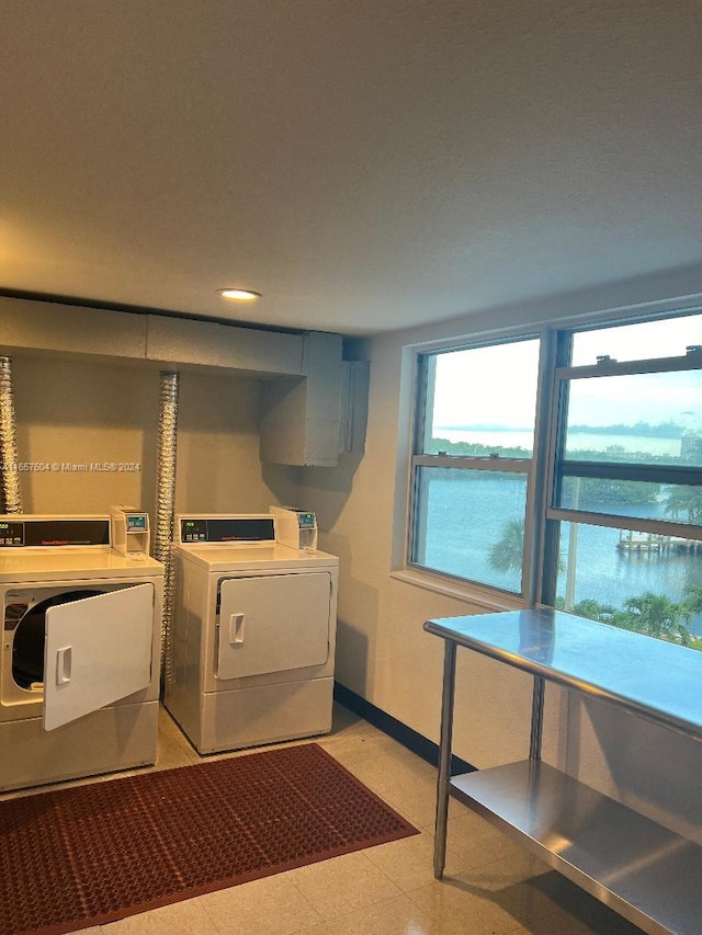 clothes washing area featuring washer and clothes dryer and a water view