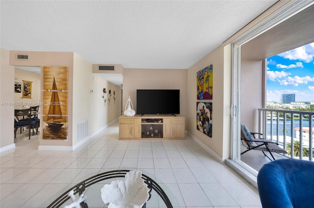 living room featuring a textured ceiling, light tile patterned floors, and a wealth of natural light