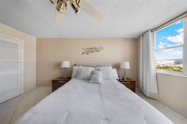 bedroom with light tile patterned floors, a textured ceiling, and ceiling fan