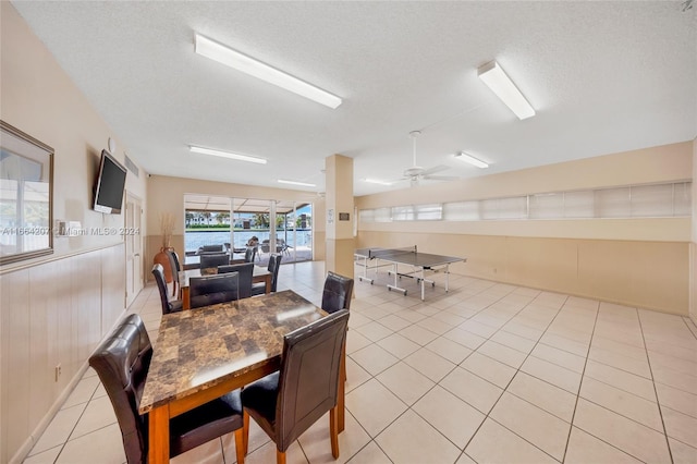 tiled dining space with wooden walls, ceiling fan, and a textured ceiling