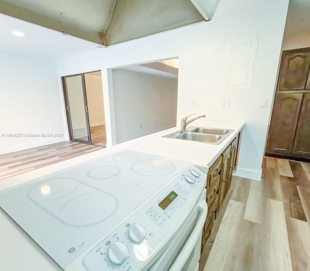 kitchen with white range with electric cooktop, sink, electric panel, and light hardwood / wood-style flooring