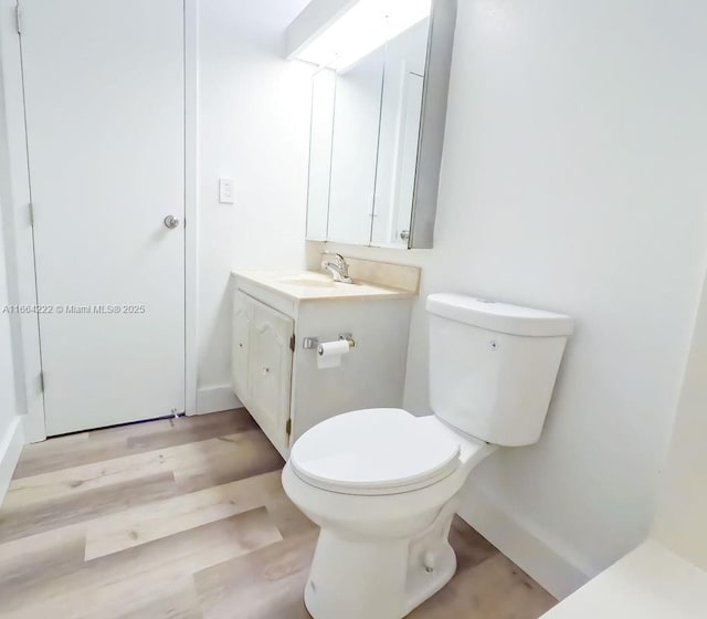 bathroom with toilet, vanity, and hardwood / wood-style floors