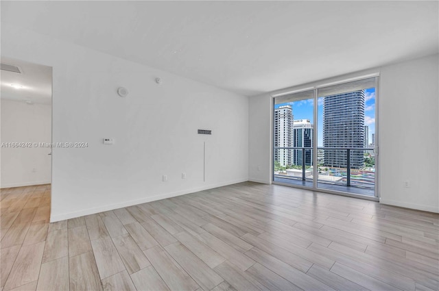 spare room featuring light wood-type flooring and expansive windows