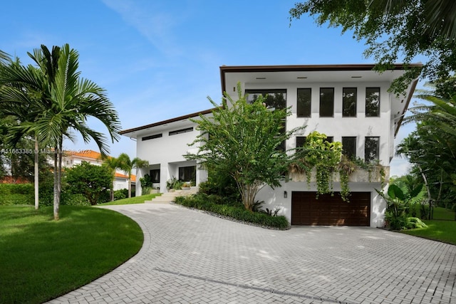 325 Campana Ave, Coral Gables, FL 33156 - contemporary house with stucco siding, decorative driveway, an attached garage, and a front yard