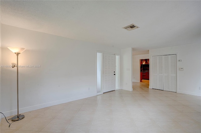 unfurnished room featuring light tile patterned flooring and a textured ceiling