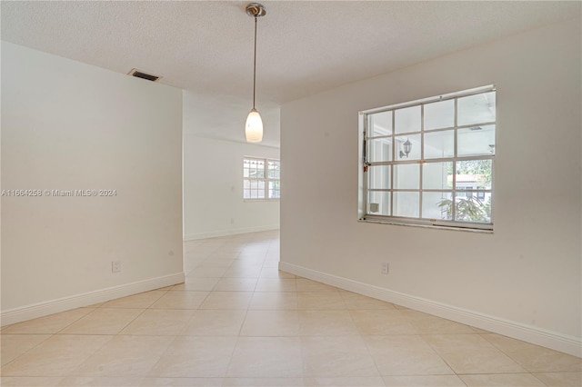 spare room featuring a textured ceiling and light tile patterned floors