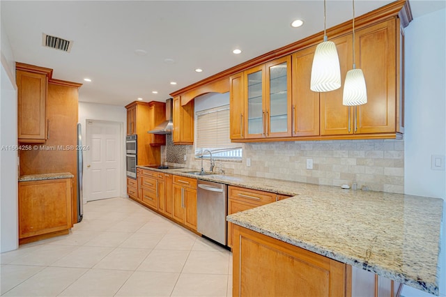 kitchen with sink, kitchen peninsula, stainless steel appliances, pendant lighting, and light stone counters