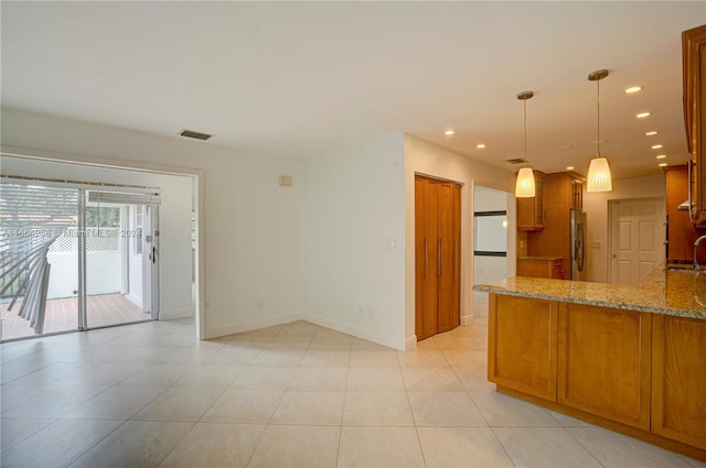 kitchen featuring sink, stainless steel fridge, pendant lighting, light stone counters, and light tile patterned floors