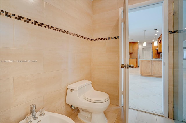 bathroom with sink, toilet, tile patterned floors, tile walls, and a bidet