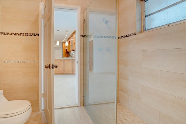 bathroom featuring tile walls, tiled shower, toilet, and tile patterned flooring