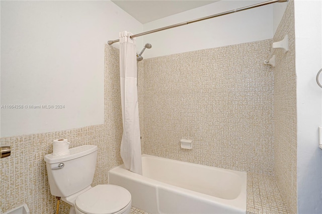 bathroom with tile walls, shower / bath combination with curtain, and toilet